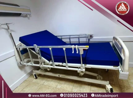 صورة طبيعية لسرير طبي كهربائي Saikang ICU بخمس حركات، هيكل أبيض متين، مرتبة طبية زرقاء، مزود بريموت، حامل محاليل، وأربع عجلات صامتة.