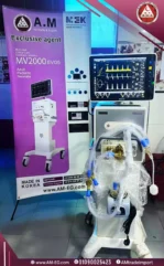 صورة حقيقية في المستشفى لجهاز تنفس صناعي MEK MV2000 EVO 5 بشاشة TFT تاتش 15 بوصة، بتصميم أبيض بقاعدة لها أربع عجلات.