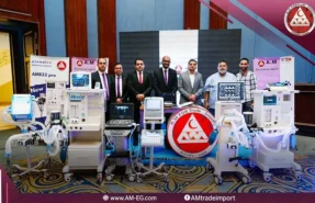 AM Company team displays white digital anesthesia machines, white and blue ventilators with touch screens, and a portable EKG machine on a white trolley with a black ultrasound.