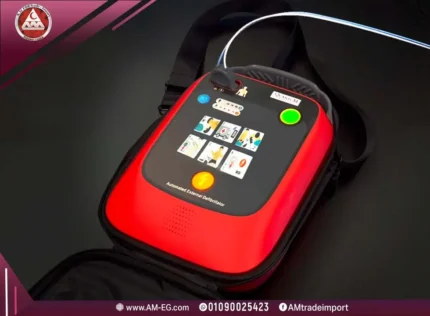 A real, top-angle photograph of a red automatic shock device with a black front panel containing visual instructions for use.