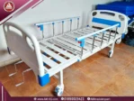 صورة طبيعية لسرير طبي 2 حركة يدوي في وضع مسطح، بتصميم معدني أبيض، بأربع عجلات، جوانب أمان.