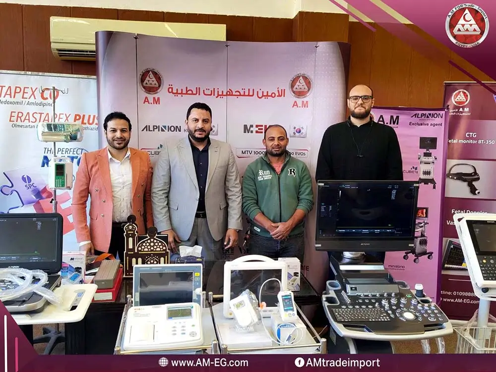طاقم شركة الأمين ميديكال في قاعة عرض للأجهزة الطبية يٌف خلف مجموعة أجهزة طبية مثل شاشات مراقبة المريض وأجهزة سونار ورسم قلب